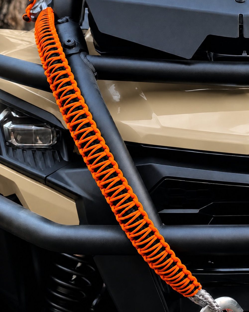 Orange and black hand-braided paracord tow cord on the front of a tan side-by-side